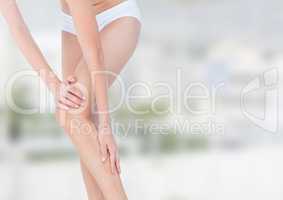 Slim woman holding her leg in front of blurred background