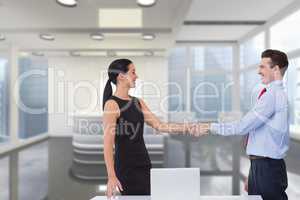 Happy business people shaking hands against office background