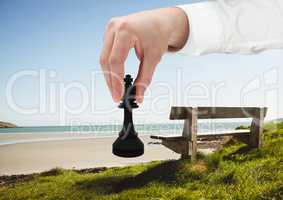 Hand holding chess piece by beach