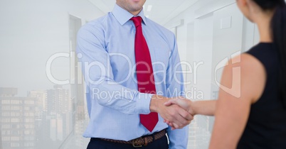 Business people shaking hands against office and city background