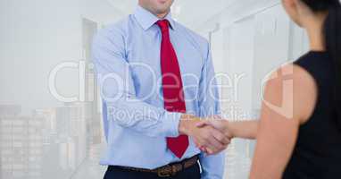 Business people shaking hands against office and city background