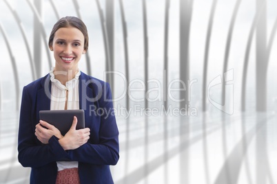 Happy business woman holding a tablet against building background