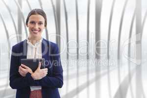 Happy business woman holding a tablet against building background