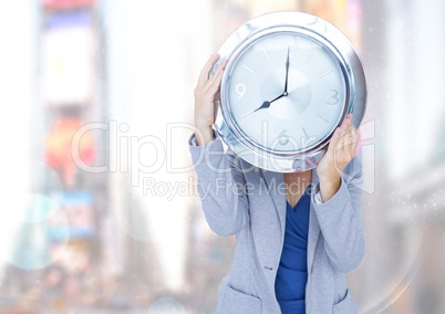 Woman holding clock in front of bright city