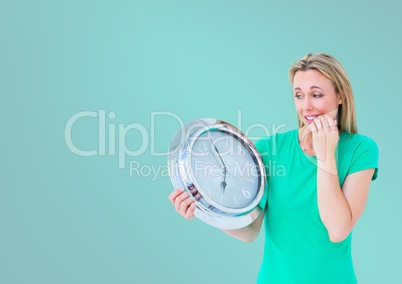 Woman holding clock in front of turquoise background