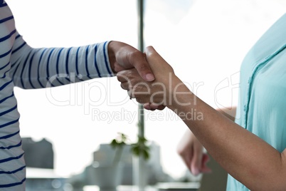 Business people shaking hands against office background