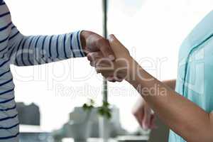 Business people shaking hands against office background