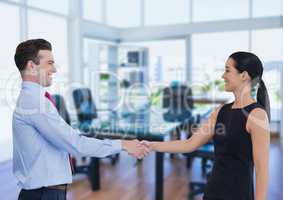 Happy business people shaking hands against office background