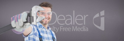 Happy mechanic man holding a wrench against purple background