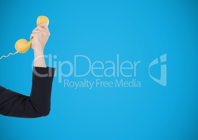 Arm holding yellow telephone on blue background