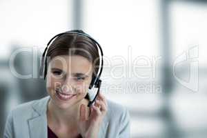 Happy business woman with earphones against blue and white blurred background