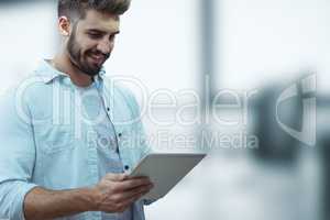Happy business man using a tablet against blue blurred background