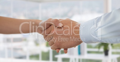 Business people shaking hands against office background