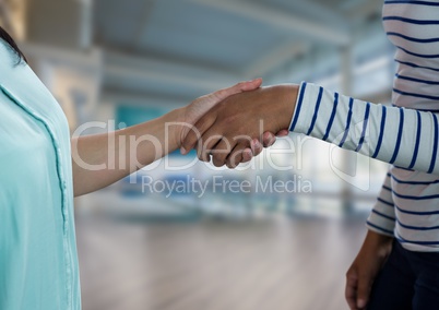 Business people shaking hands against office background