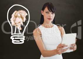 Woman with tablet standing next to light bulb with crumpled paper ball in front of blackboard