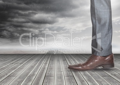 Mans leg and foot on wood with dark clouds