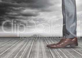 Mans leg and foot on wood with dark clouds