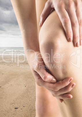 Hands holding leg on beach