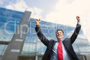 Excited business man standing against building background