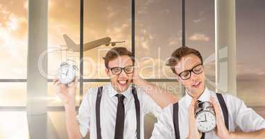 Twin hipster men holding clocks in airport