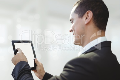 Happy business man using a tablet against white blurred background Happy business man using a tablet against white blurred background