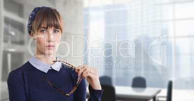 Business woman holding her glasses against office background