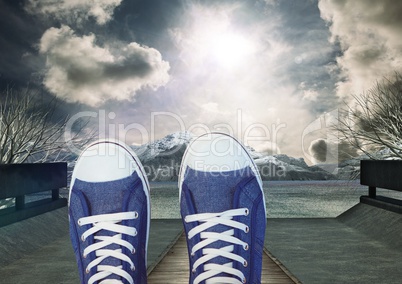 Shoes relaxing feet in front of dramataic sky clouds and mountain trees