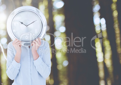 Woman holding clock in front of forest