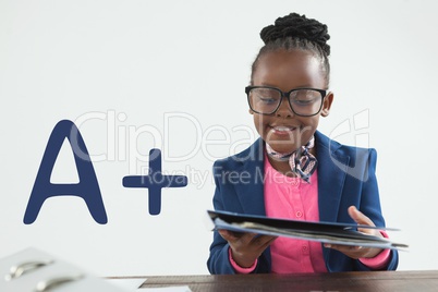 Happy office kid girl reading against white background with A+ text