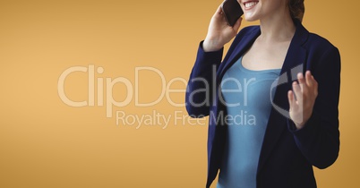 Happy business woman talking on the phone against orange background