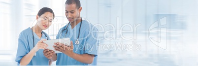 Doctors looking at a tablet against blue background
