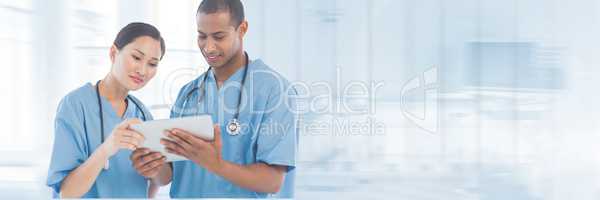 Doctors looking at a tablet against blue background