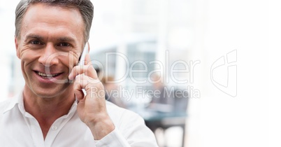 Happy business man talking on the phone against office background