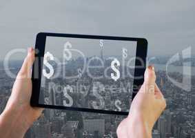 Holding tablet and Dollar icons over city