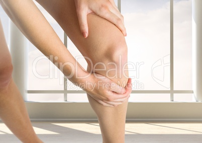 Woman holding her leg by windows