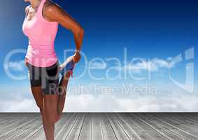 Woman stretching leg in front of sky