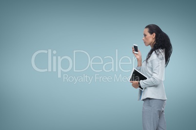 Business woman holding a phone and a tablet against blue background