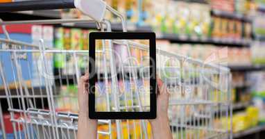 Hand taking picture of shopping cart with tablet PC in grocery store