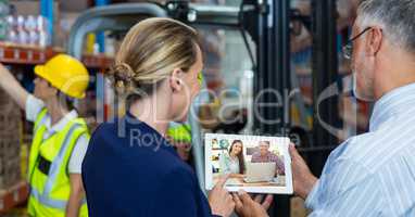 Business people video conferencing on tablet PC in warehouse