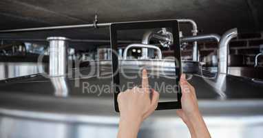 Hand photographing lid of container through digital tablet at brewery