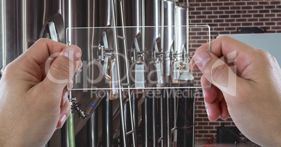 Hands photographing machinery through transparent device at brewery