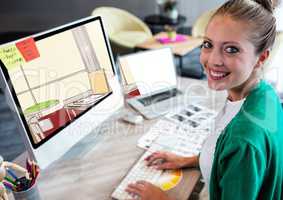 woman smiling working on the computer with draw of new office design (color: green and red)