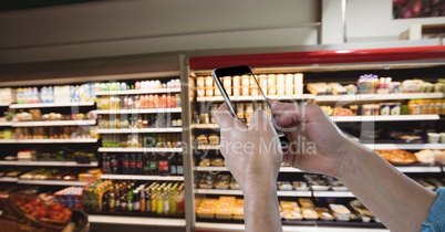 Hand photographing products through smart phone at grocery shop