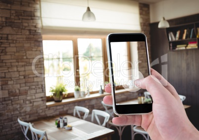 Hand of person taking a picture of a dinning room with her smartphone