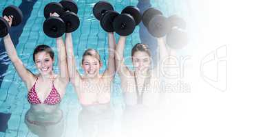 Smiling women lifting dumbbells in swimming pool