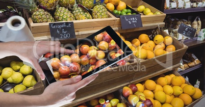 Hands photographing apples through digital tablet at grocery shop