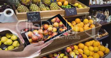Hands photographing apples through digital tablet at grocery shop