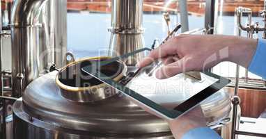 Hands photographing vats through digital tablet at brewery