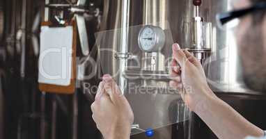 Man taking picture of machinery through transparent device at brewery