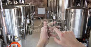 Hands photographing containers through transparent device at brewery